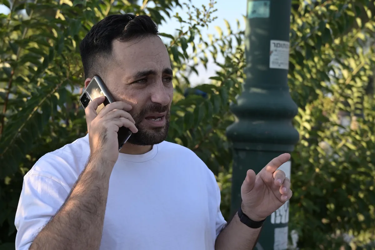 ניב איפרגן מדבר בטלפון בחוץ ומחווה ביד השנייה